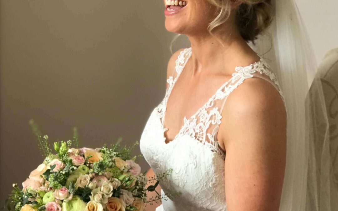 smiling blonde bride with hair pinned up with long veil subtle natural makeup, rose bouquet with butterflies