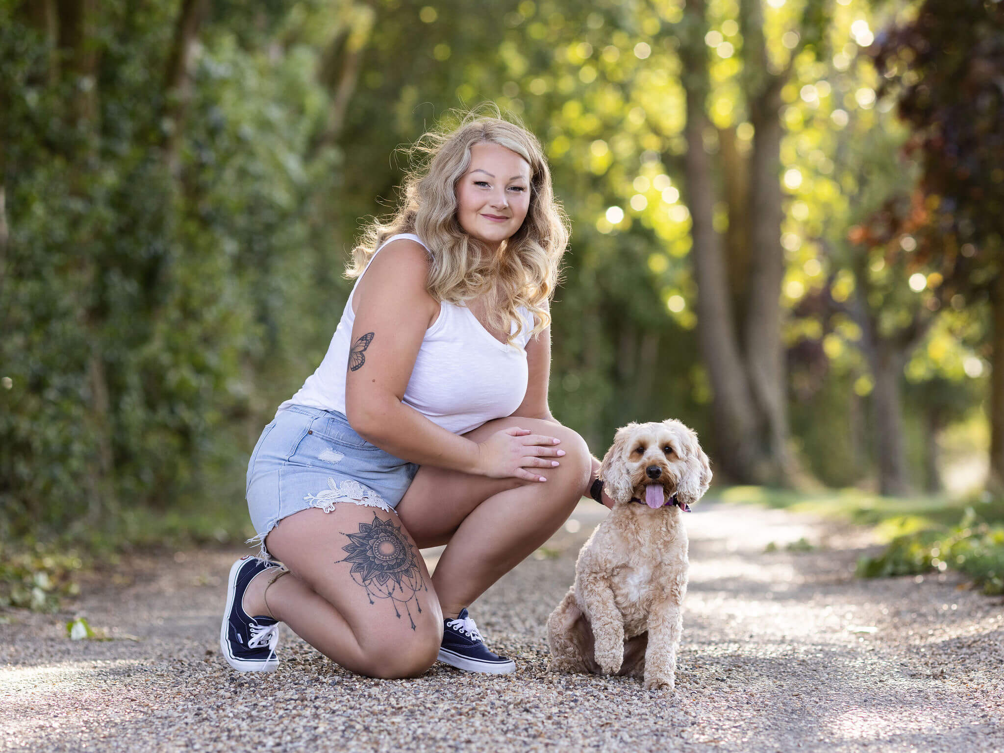 blonde model with natural curls, hair and makeup, tattoos, outside photoshoot with cockapoo,